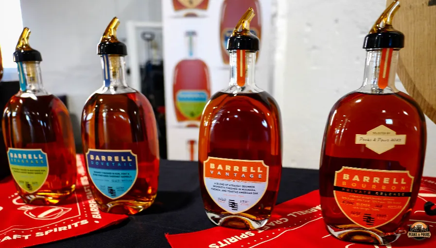 Barrell Bourbon private release bottles and tasting glasses on branded display at Peaks and Pours 2023
