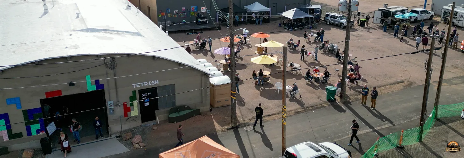 Aerial view of Meanwhile Block venue exterior in Colorado Springs with attendees arriving at the inaugural Peaks and Pours spirits festival