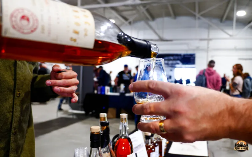 Attendee receiving a pour of Doc Swinson's whiskey at Peaks and Pours 2023